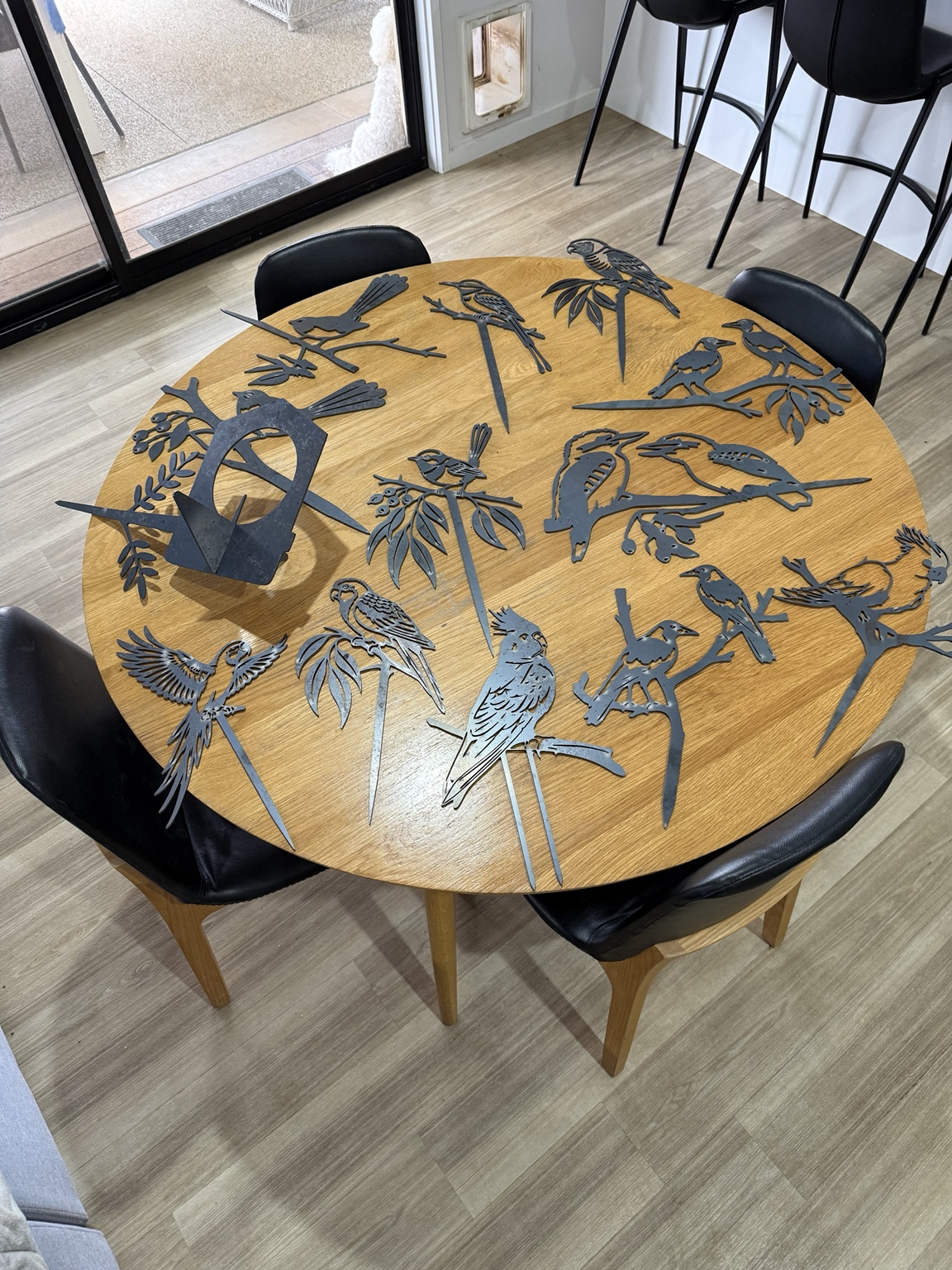 Laser cut native bird garden stakes arranged on a round table for a photo